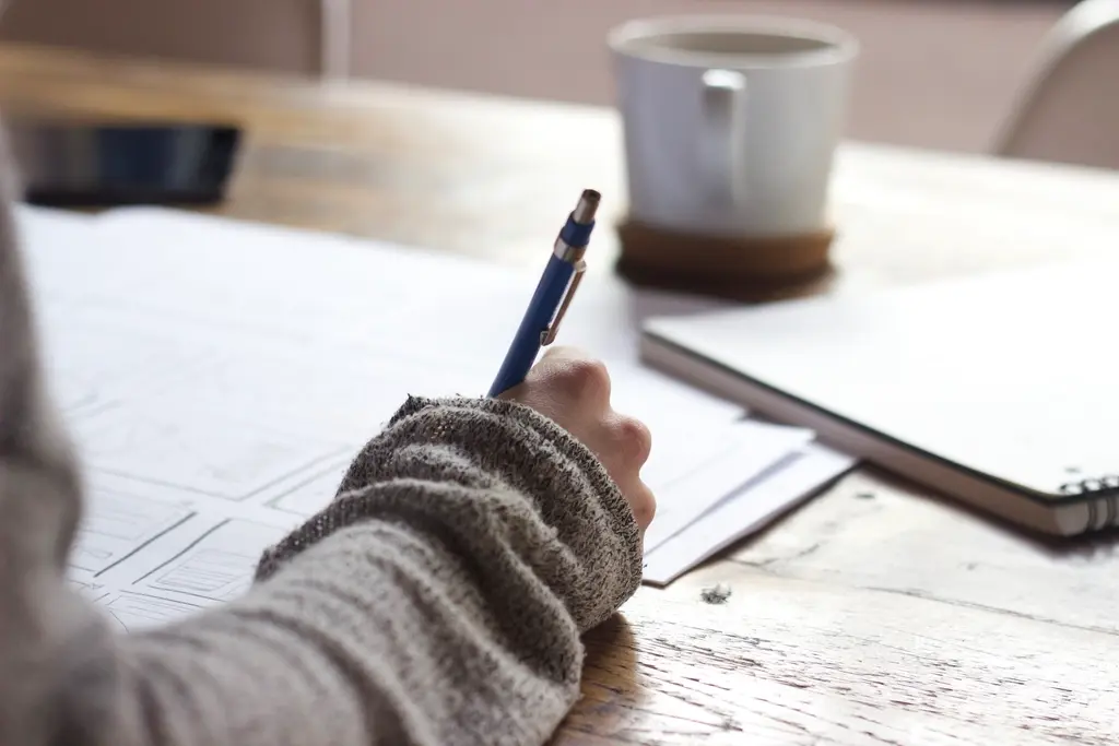 Designer sketching wireframes and system diagrams on paper