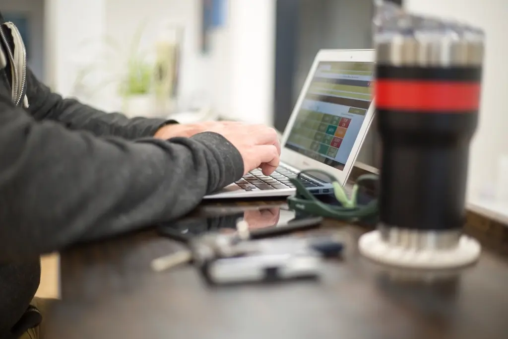 Person working on a laptop at home while reviewing project details
