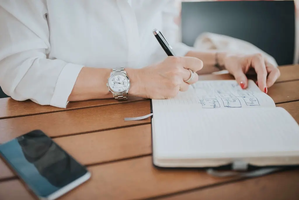 Person writing notes on a notepad while planning a project