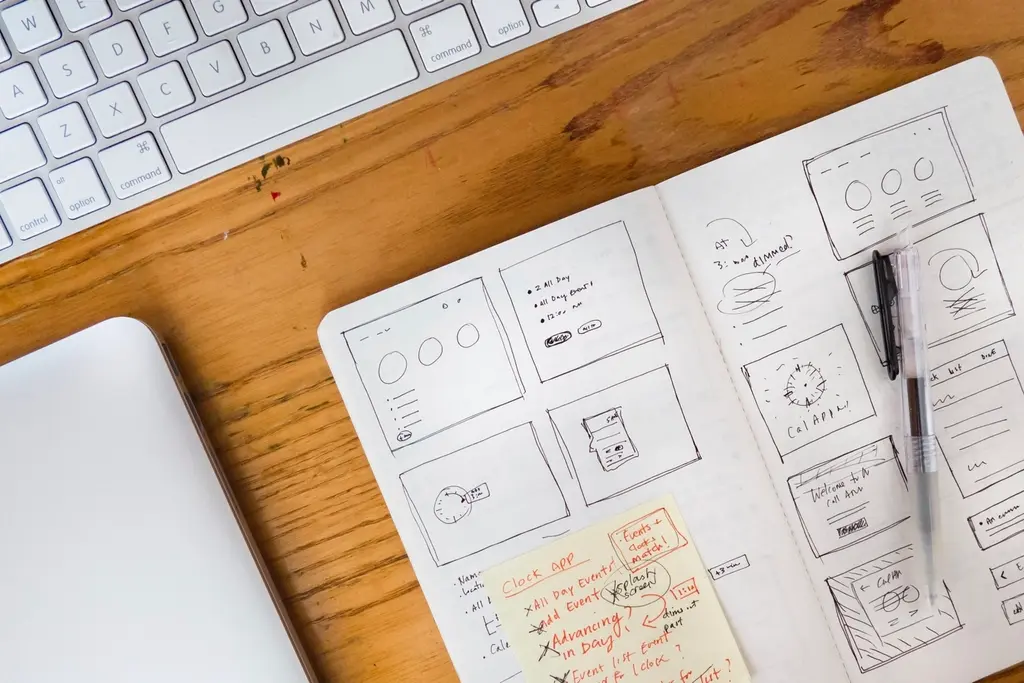 Organized web design workspace with a laptop, notes, and reference materials