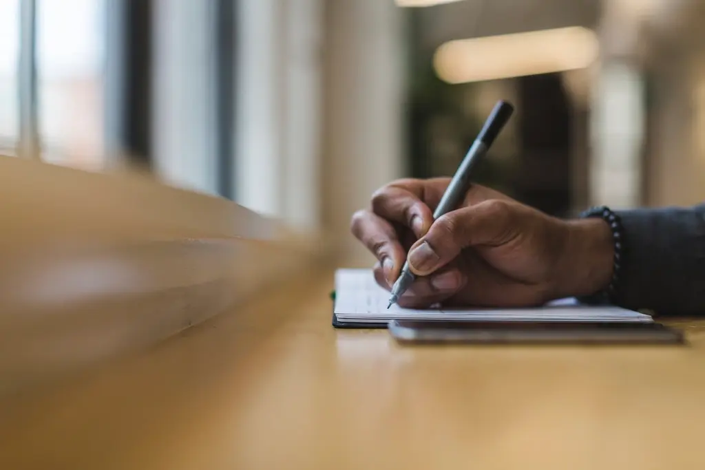 Person taking notes while planning a marketing campaign