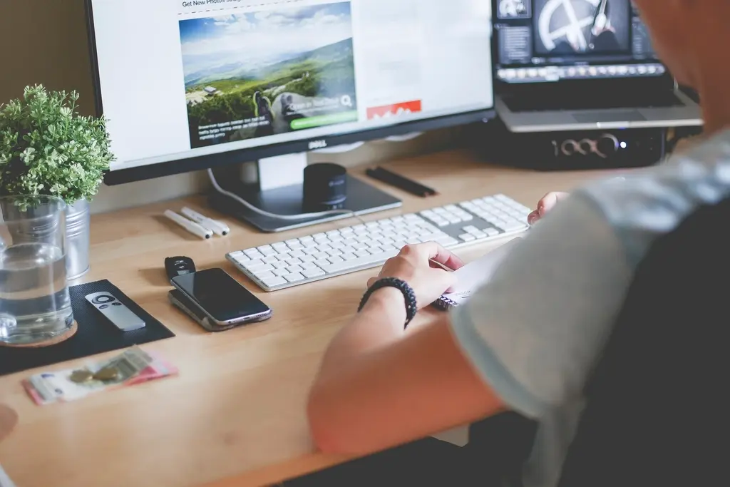 Web designer planning a website layout on paper next to a laptop