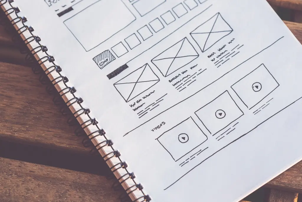 Web design wireframes and sketches spread across a desk during a planning session